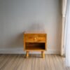 Enhance your space with The Single Drawer Teak Nightstand, featuring solid teak wood, natural satin finish, and a practical open drawer design.