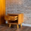 Enhance your space with The Single Drawer Teak Nightstand, featuring solid teak wood, natural satin finish, and a practical open drawer design.